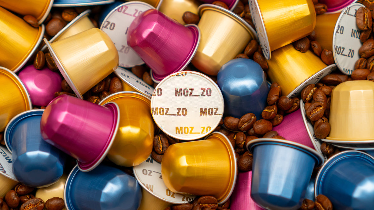 Coloured coffee pods amongst roasted coffee beans