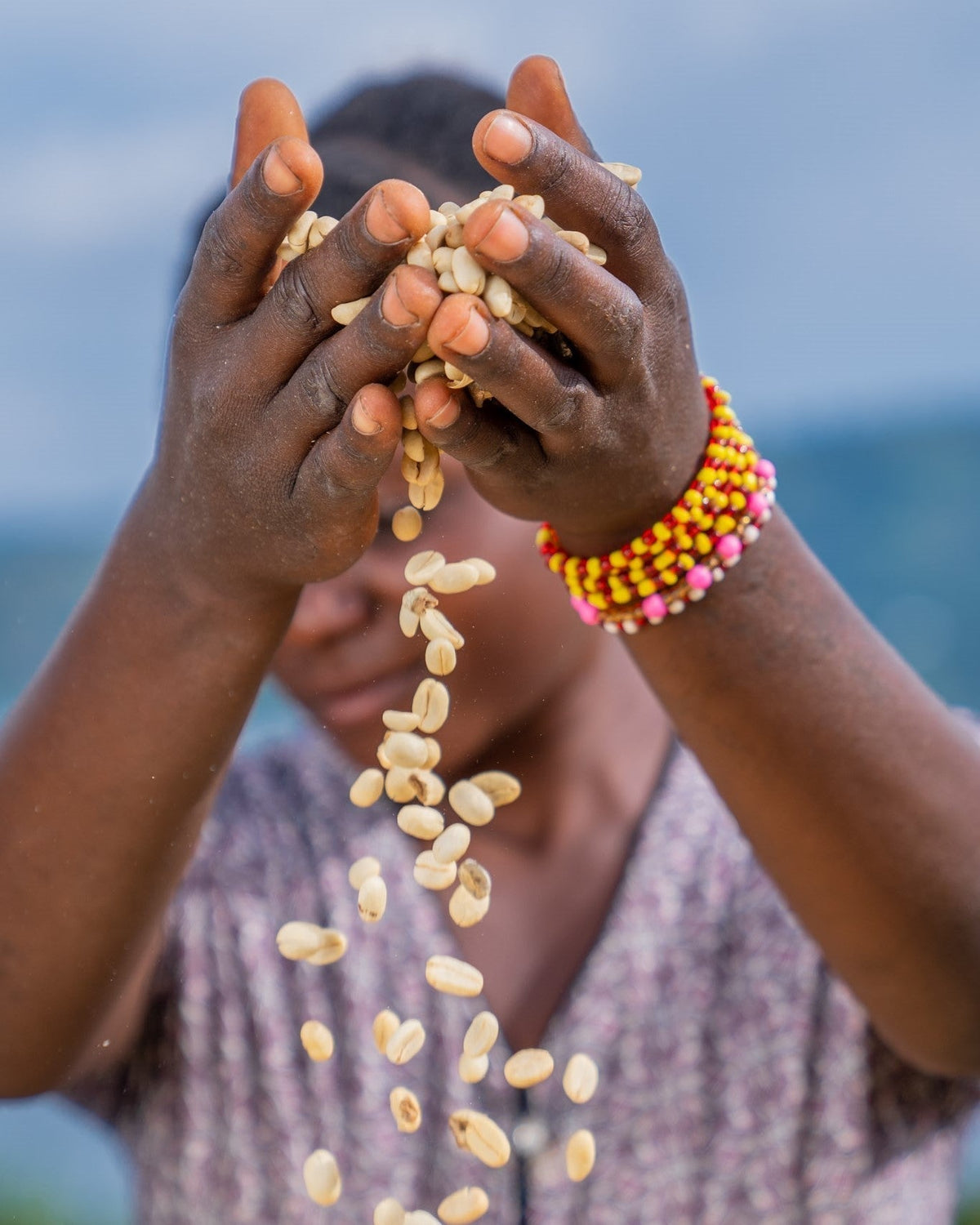 African woman throwing green coffee beans