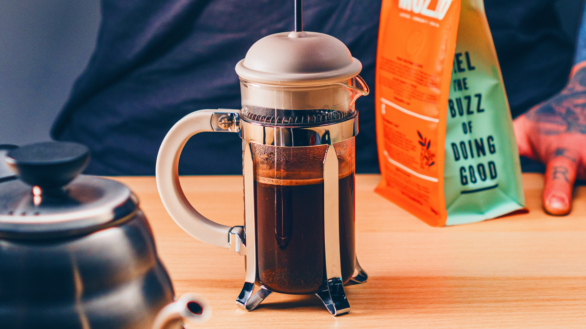 Decaf coffee brewing in a cafetiere next to a bag of Mozzo ground coffee