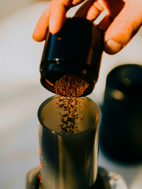 Ground coffee being poured into an AeroPress 