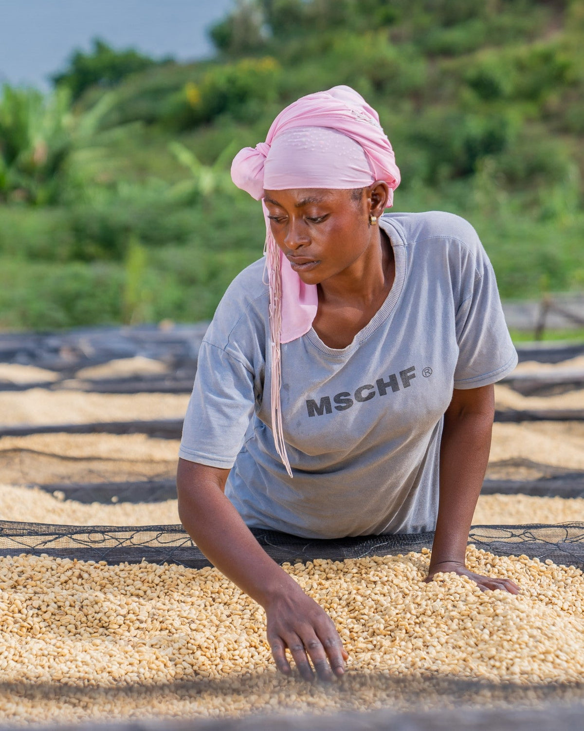 A woman from Idjwi Island's coffee farming community drying coffee beans