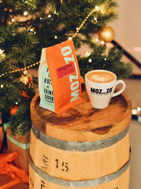A Christmas spiced butter latte made with Mozzo coffee next to a twinkling Christmas tree 