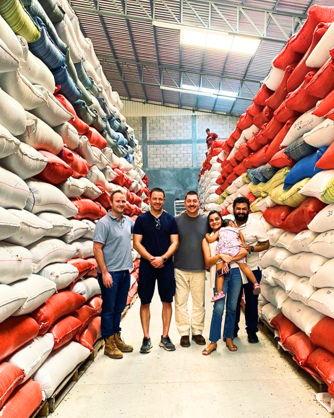 Grant Lang with the coffee farming family standing amongst a high stack of raw coffee beans 