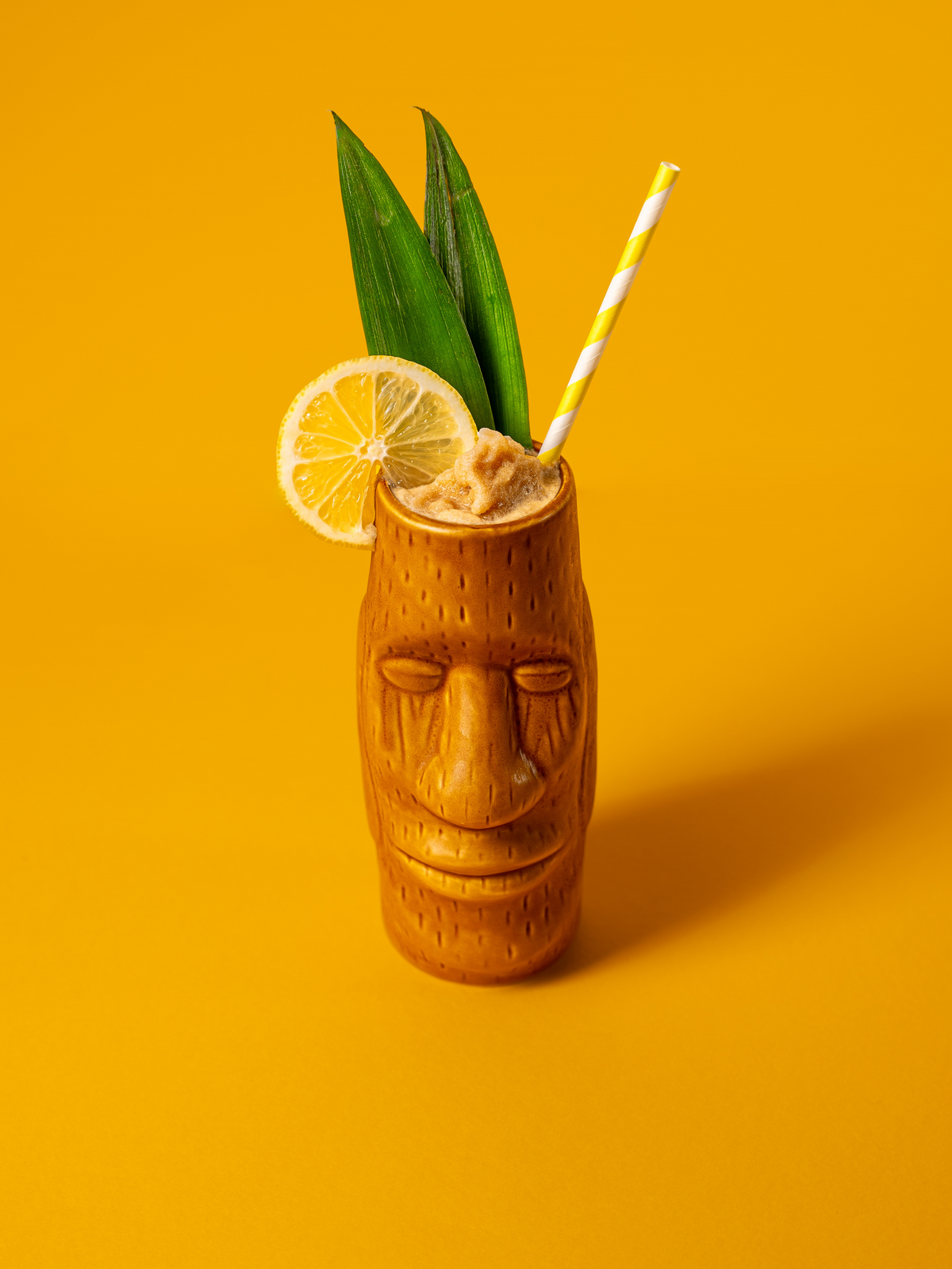 a tiki tumbler featuring a coffee colada with lemon and pineapple leaves 