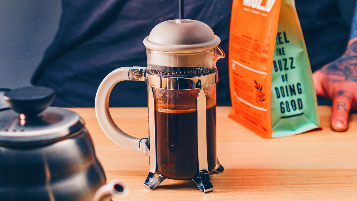 Decaf coffee brewing in a cafetiere next to a bag of Mozzo ground coffee 